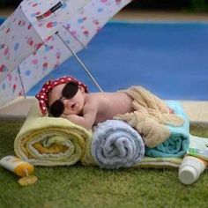 a baby laying on top of a towel next to an umbrella