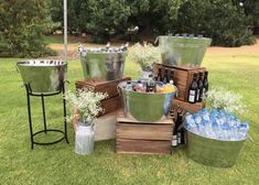 several metal buckets filled with bottles and water on top of grass next to trees