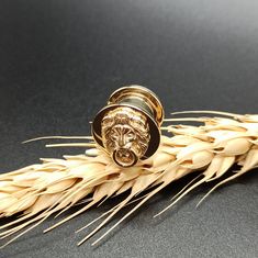 a gold ring with a lion's head on it sits in the middle of some wheat