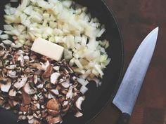 mushrooms, onions and cheese are in a skillet with a knife on the side