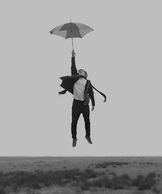 a man flying through the air while holding an umbrella