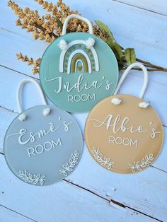 three personalized door hangers on a white wooden surface with flowers and leaves in the background