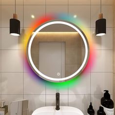 a bathroom sink with a round mirror on the wall above it and two black soap dispensers next to it