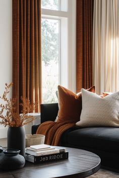 a living room filled with furniture and a window covered in orange drapes next to a coffee table