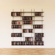 a book shelf filled with lots of books on top of a hard wood floor next to a white wall