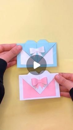 two hands holding origami envelopes with bow ties