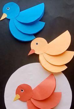 two paper birds sitting on top of a table next to each other, one is orange and the other is blue