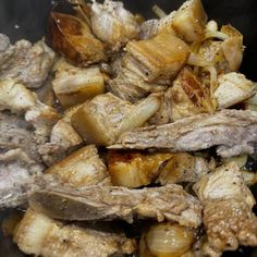 meat and onions cooking in a pan on the stove top with oil coming from it