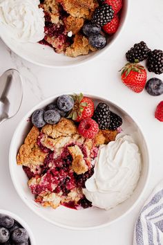 two bowls filled with fruit and ice cream on top of a white counter next to spoons