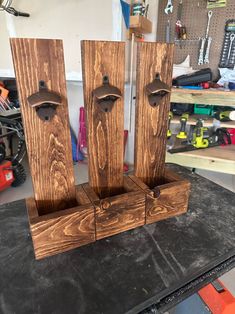 three wooden door handles on a table in a garage with tools and other items behind them