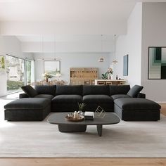 a living room filled with black couches and furniture in front of a large window