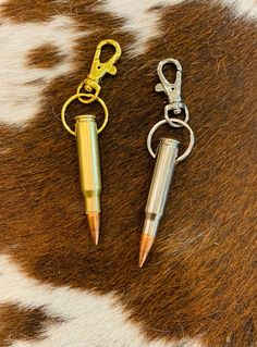 two metal pens sitting on top of a cowhide rug next to a keychain