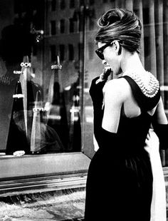 a woman in a black dress is talking on her cell phone