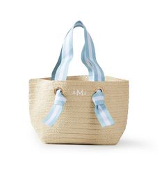 a blue and white striped straw tote bag with monogrammed ribbon on the handles