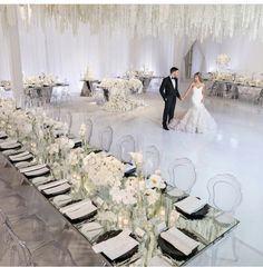 a bride and groom holding hands in front of an elegant table set for their wedding reception