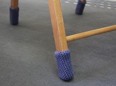 a close up of a child's wooden swing with blue crocheted handles