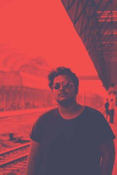 a man standing in front of a train station with red light coming from the ceiling