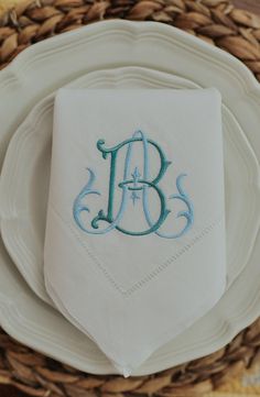 the monogrammed napkin is on top of an empty white plate with blue lettering