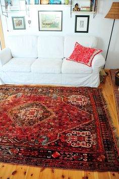 a living room with a white couch and red rug