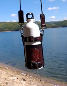 a water bottle hanging from a rope next to the ocean