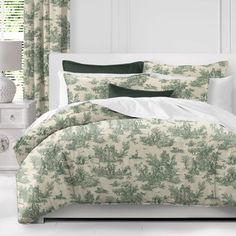 the comforter is made up with green and white floral designs on it, along with two pillows