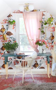 a room with floral wallpaper and chairs in front of a large window that has pink curtains