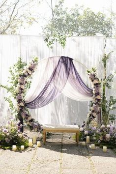 an outdoor ceremony setup with flowers and candles on the ground, in front of a white backdrop