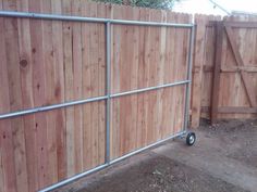 a wooden fence with metal bars and wheels on it's sides in front of a gate