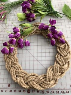 a rope wreath with purple flowers on it next to a ruler and measuring tape,