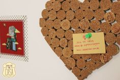 a heart shaped cork board with a note attached to it and two pictures on the wall