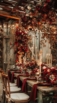 a long table with candles and red flowers on it is set for an elegant dinner