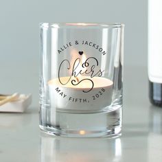 a personalized glass candle holder on a table next to a wine bottle and corkscrew