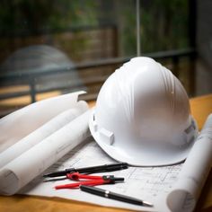 a hard hat and some construction tools on top of blueprint