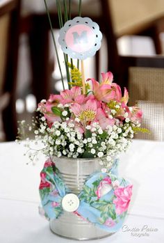 a vase filled with pink flowers on top of a white table cloth covered tablecloth