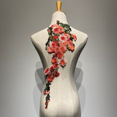 a white mannequin with red flowers and green leaves on it's back