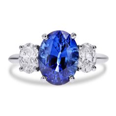 an oval blue and white sapphire ring with three diamonds on the band, set in 18k white gold