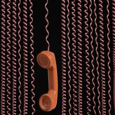 an orange phone hanging from a wall with red spirals on it's sides