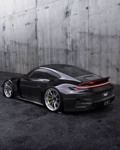 a black sports car parked in front of a concrete wall