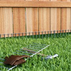 a lawn mower laying in the grass next to a fence