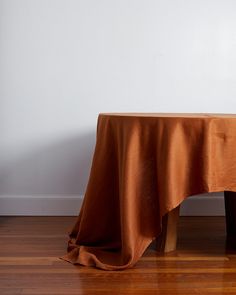 an orange table cloth on top of a wooden chair in front of a white wall