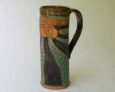 a green and brown vase sitting on top of a white table