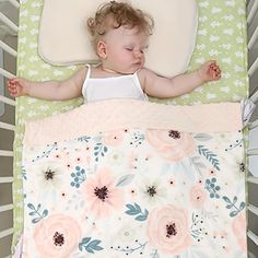 a baby sleeping in a crib with flowers on it's blanket and pillow