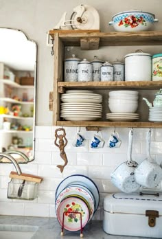 an old fashioned kitchen with dishes and pans hanging on the wall next to it