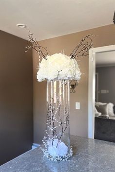 a vase filled with white flowers on top of a counter next to a light fixture