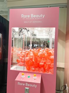 a pink display case with orange balloons in the shape of balls on it's sides