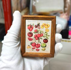 a person holding up a small wooden frame with fruit on it