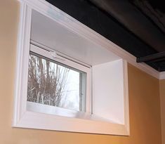 an open window in the corner of a room with yellow walls and white trim on it