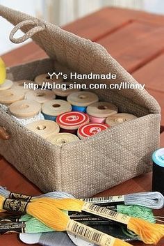 a basket filled with lots of different types of thread and spools on top of a wooden table