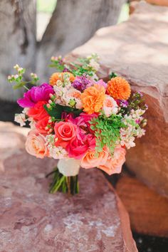 a bouquet of colorful flowers sitting on top of a stone slab next to a tree