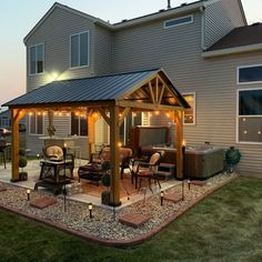 a covered patio with hot tub and lights on the side of it at night in front of a house